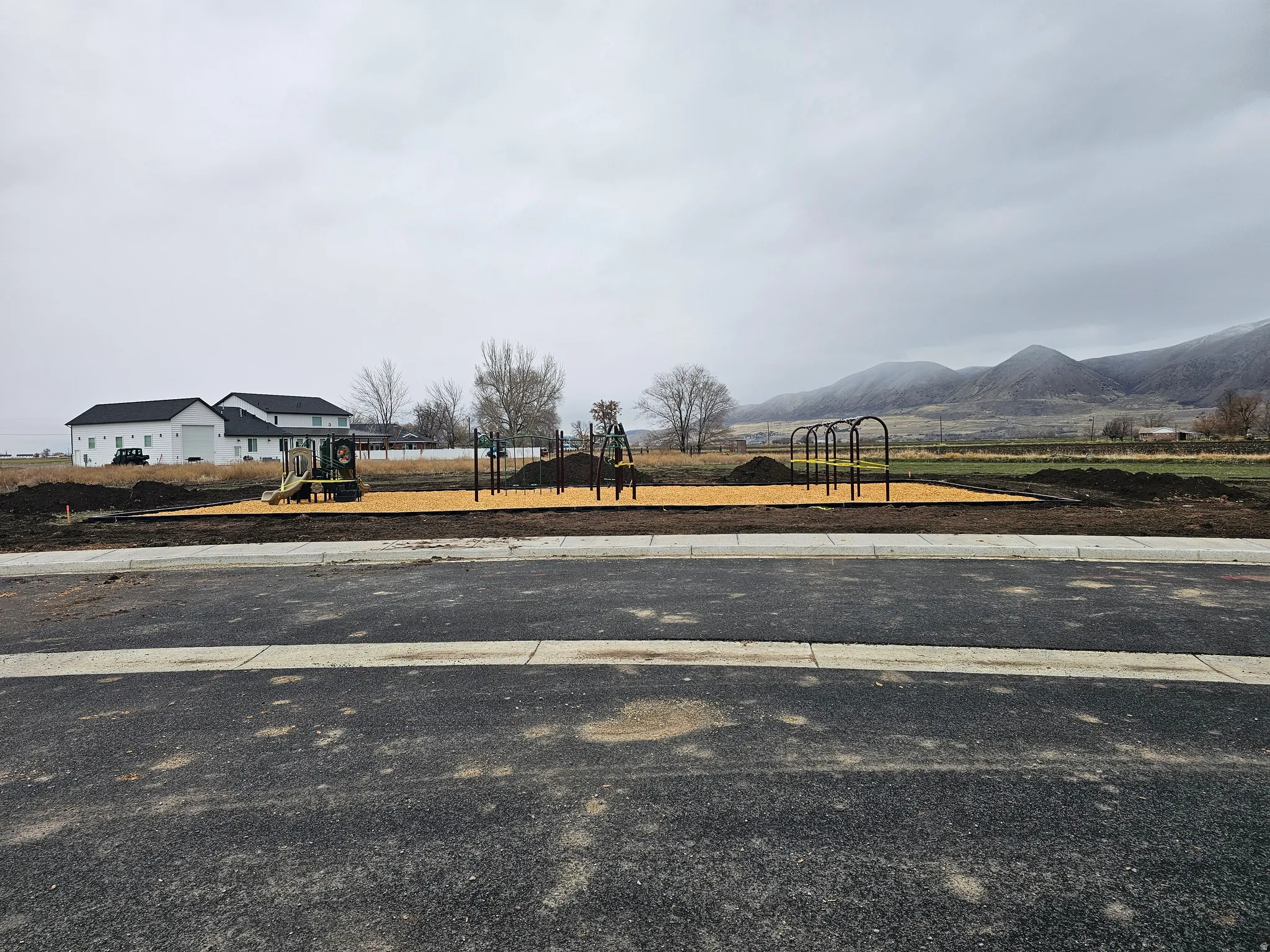 Community playground featuring multiple play structures on a wood chip base