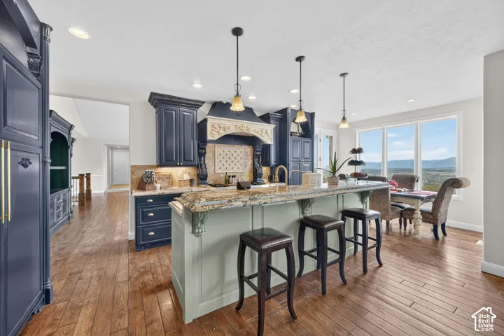 Open-concept kitchen featuring dark wood cabinetry, a light-toned island with decorative corbels, and stone countertops