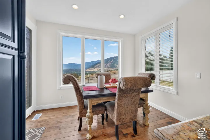 Dining area featuring a large window with mountain scenery, white trim throughout, recessed lighting, and wood-finish flooring