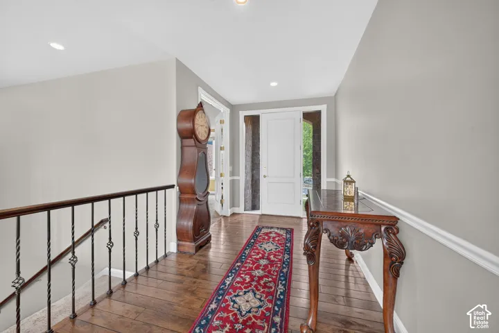 Entryway featuring wood-finish flooring, recessed lighting, a white paneled front door with sidelight, and a wrought iron stair railing with a wood-finish handrail