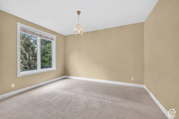 Neutral-toned room featuring a decorative chandelier and a large window overlooking lush greenery