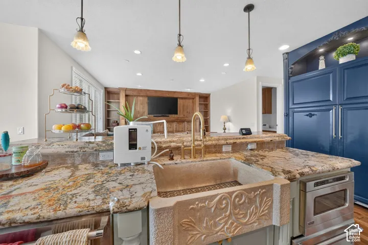 Kitchen island featuring an ornate farmhouse sink, gold-toned faucet, and granite countertops