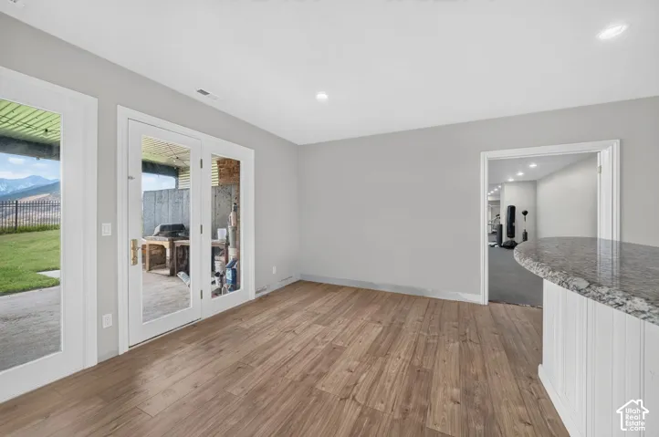 Spacious room featuring wood-finish flooring, recessed lighting, and a neutral wall color