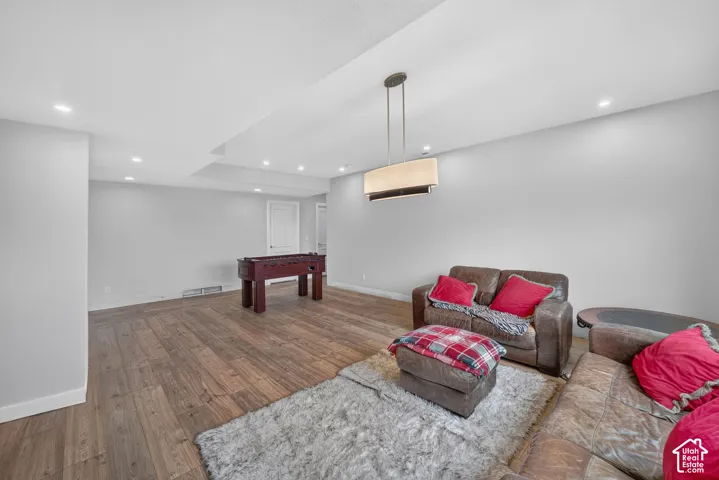 Spacious recreational area featuring wood-finish flooring, recessed lighting, and a contemporary chandelier