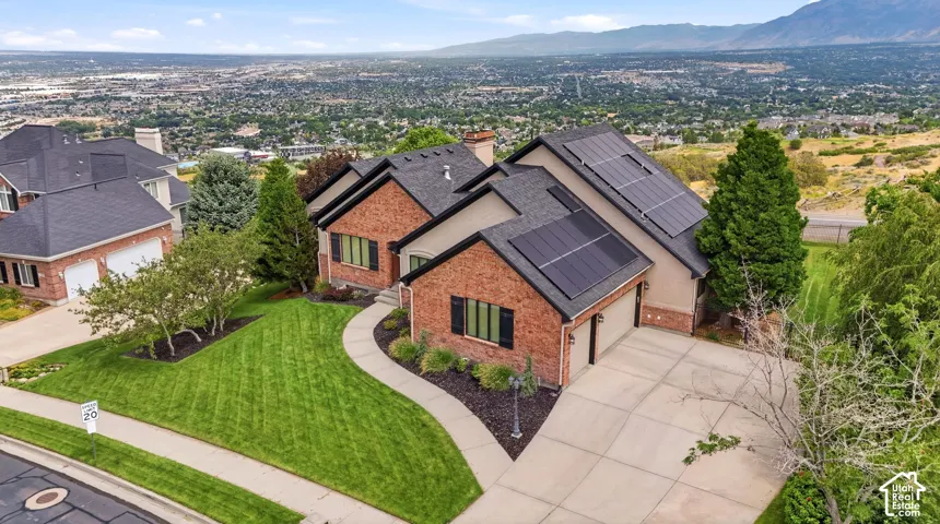 Red brick exterior with a tan stucco accent, featuring a two-car garage, solar panels, and a concrete driveway
