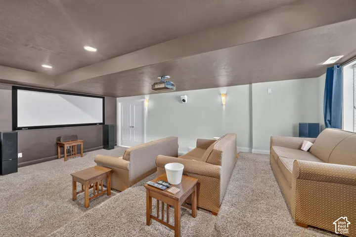 Media room featuring a large projection screen, recessed ceiling lighting, a ceiling-mounted projector, and sconce lighting