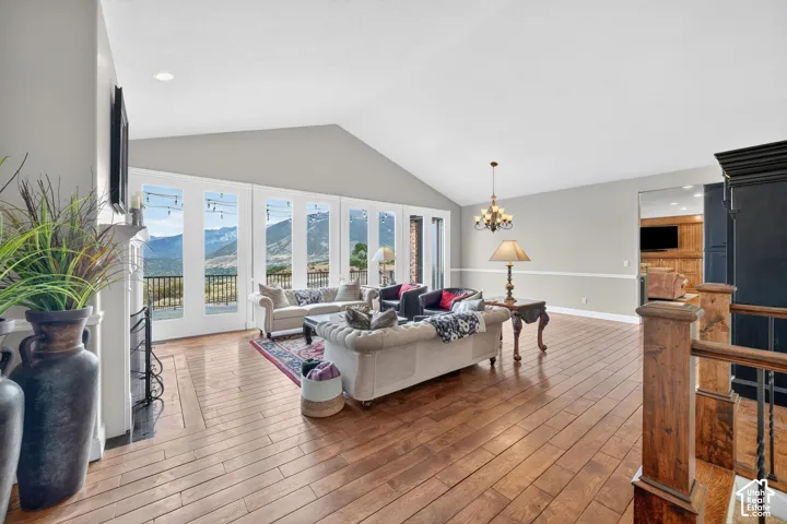 Spacious living area featuring wood-finish flooring, a vaulted ceiling, and an abundance of natural light from multiple glass-paneled doors