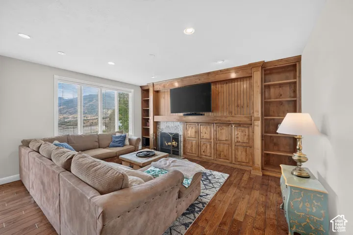 Living area featuring wood-finish flooring and a built-in entertainment center with shelving and storage cabinetry