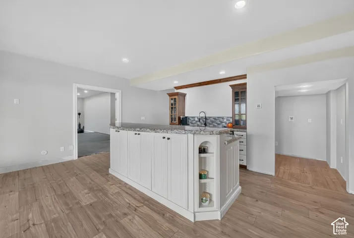 Kitchen island featuring white cabinetry, a granite-look countertop, and integrated shelving