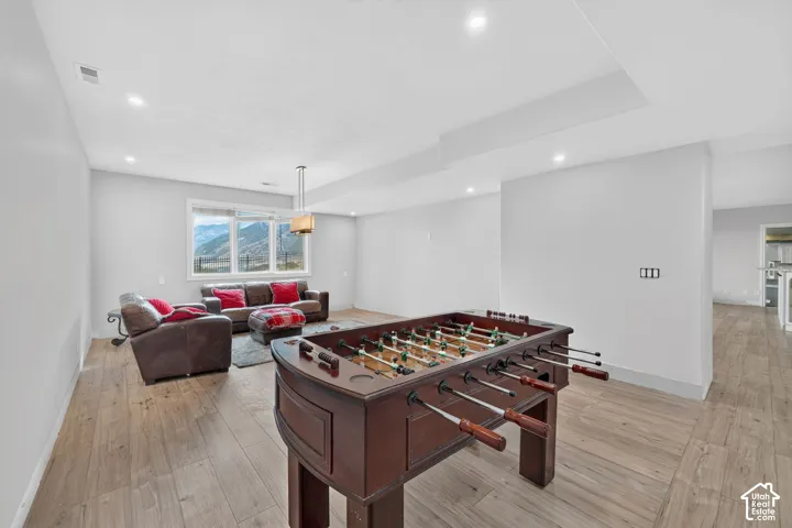 Spacious recreation room featuring wood-finish flooring, recessed lighting, and a large window offering mountain scenery