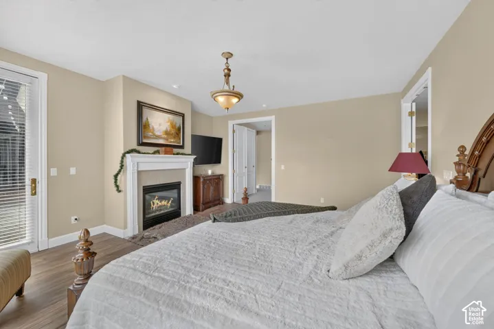 Interior room with wood-finish flooring, a white mantel fireplace with a dark hearth, and a white trim glass-paned door