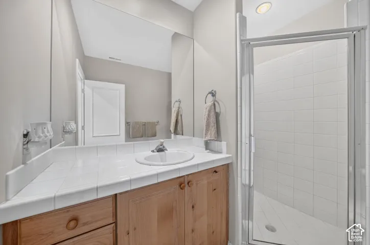 Bathroom featuring a walk-in shower with a glass enclosure, white subway tile surround, and a built-in light fixture