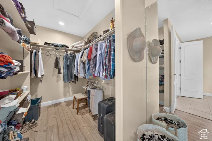 Spacious closet featuring wood-finish flooring, recessed lighting, and extensive built-in shelving