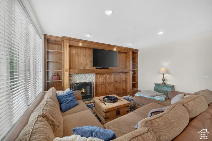 Living area featuring a floor-to-ceiling built-in entertainment center with a fireplace, stone surround, and integrated shelving