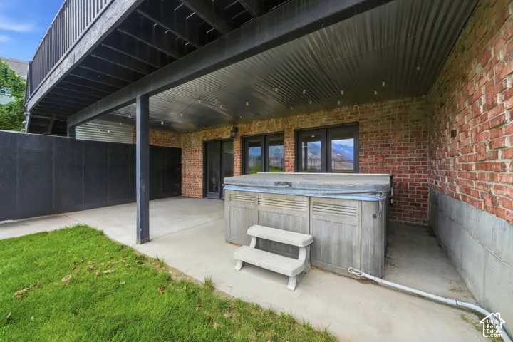 Covered patio with a built-in hot tub, concrete flooring, and a corrugated metal ceiling