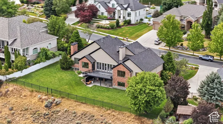 Expansive rear yard with a manicured lawn, established landscaping, and black iron fencing