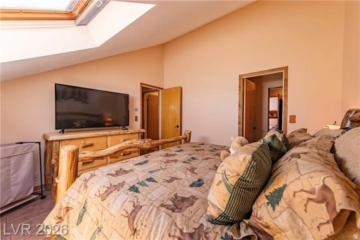 Vaulted ceiling with skylight and light wood trim, complemented by wood-finish flooring