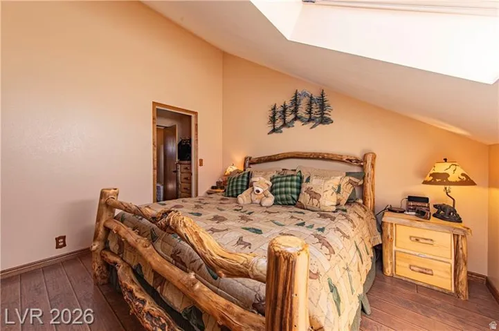Room featuring a vaulted ceiling with skylight, wood-finish flooring, and a wood door frame