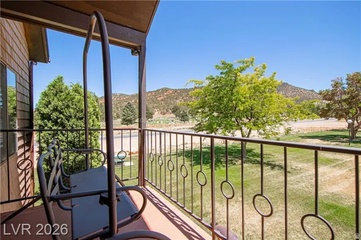 Covered balcony featuring a metal railing with circular accents, wood-paneled exterior siding, and distant mountain scenery