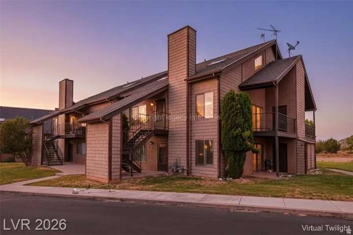 Multi-level building with shingle siding, multiple balconies with metal railings, exterior staircases, and a sloped roofline