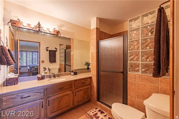 Bathroom featuring a wood-finish vanity with an integrated sink and light-toned countertop
