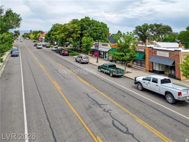 Commercial storefronts featuring brick and stucco facades, green awnings, and an asphalt street with marked lanes