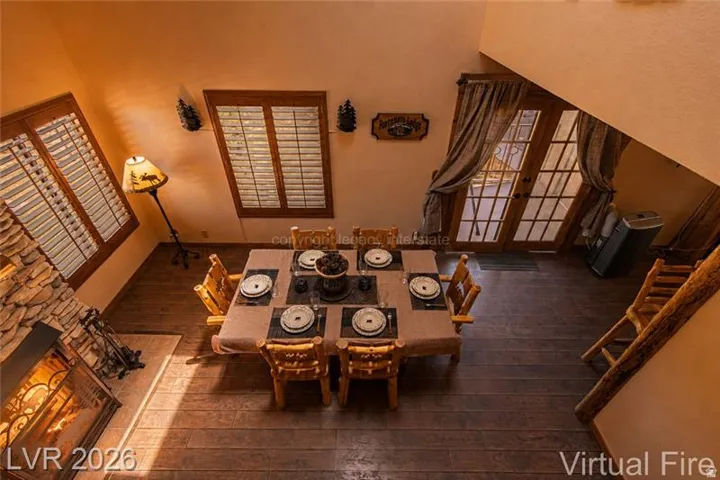 Spacious living area featuring wood-finish flooring, a stone-faced fireplace, and French doors