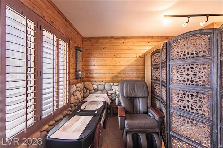 Interior space featuring horizontal wood paneling, a river rock wainscoting, and wood-framed plantation shutters