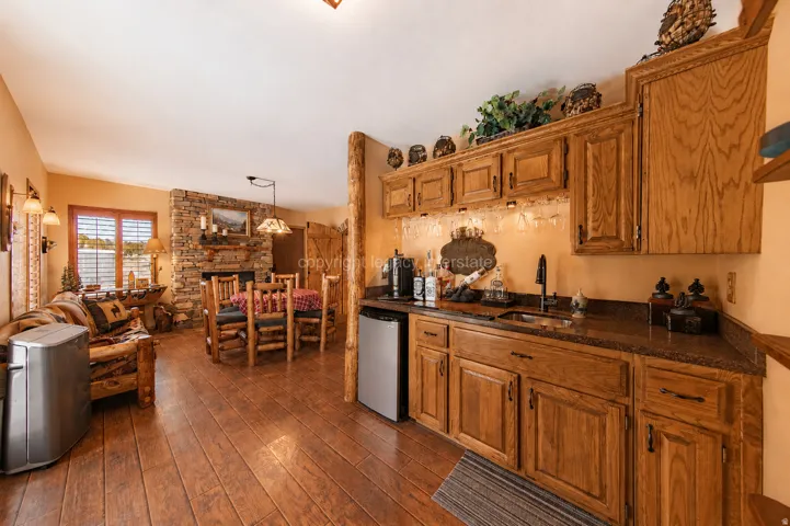 Integrated wet bar featuring wood cabinetry, stone-look countertops, and an undermount sink