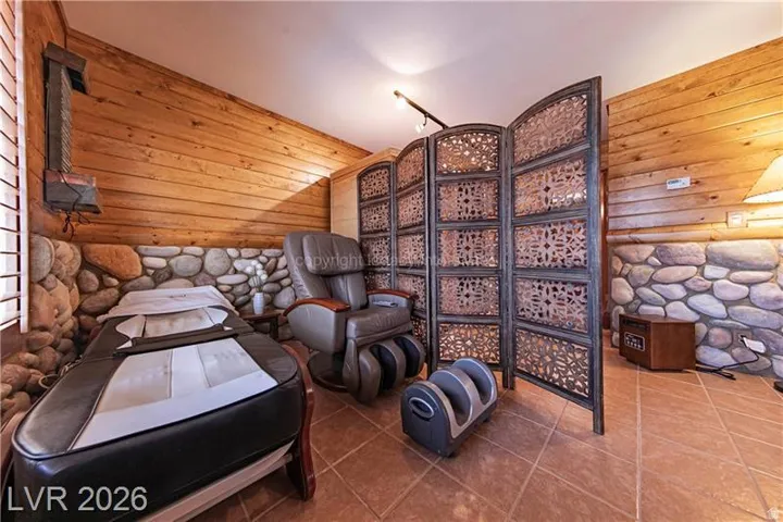 Interior space featuring wood paneling, a stone accent wall, decorative privacy screen, and diagonal tile flooring