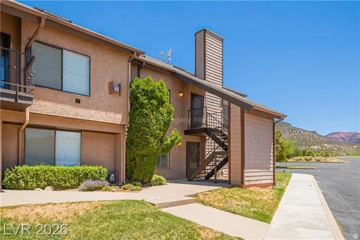 Multi-level exterior featuring stucco and shingle siding, an external staircase with metal railing, and a ground-floor patio