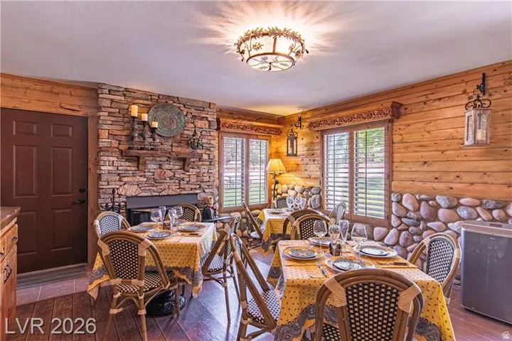 Rustic dining area featuring a stone-faced fireplace with a wood mantel