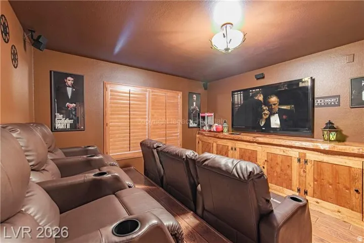 Dedicated media room featuring wood-finish flooring and a built-in wood media console