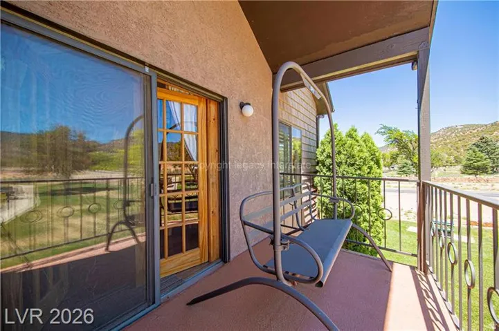 Private balcony with textured stucco exterior, sliding glass door entry, and decorative metal railing
