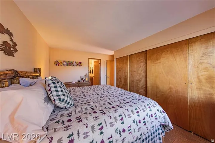 Spacious bedroom featuring warm-toned walls, wood-finish flooring, and a rustic log-style bed frame