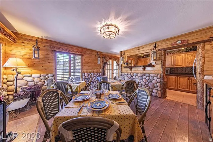 Dining area featuring wood-finish flooring, wood plank walls, and a stone accent wall