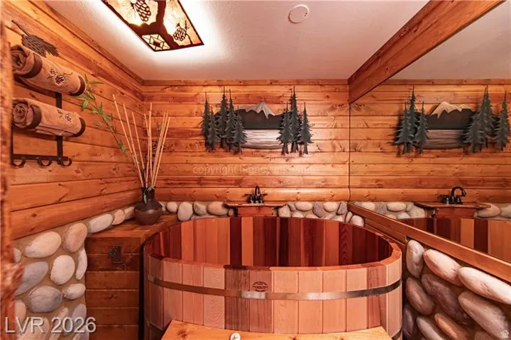 Wood-paneled room featuring a large wooden soaking tub with metal banding