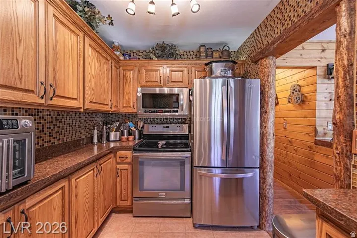 Kitchen featuring wood cabinetry, stainless steel appliances, mosaic tile backsplash, and a wood-finish countertop