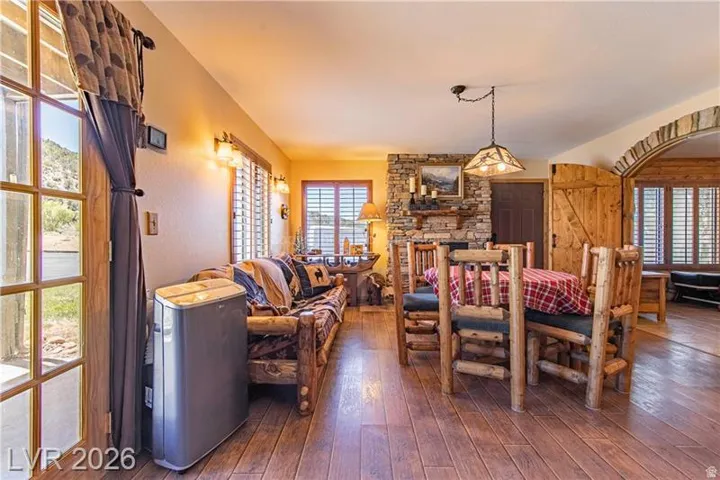 Open-concept living space featuring wood-finish flooring, a stone fireplace, and wood plantation shutters