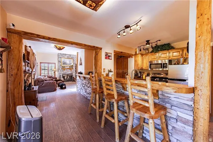 Kitchen featuring wood-finish cabinetry, stainless steel appliances, and a stone-clad island with a wood countertop