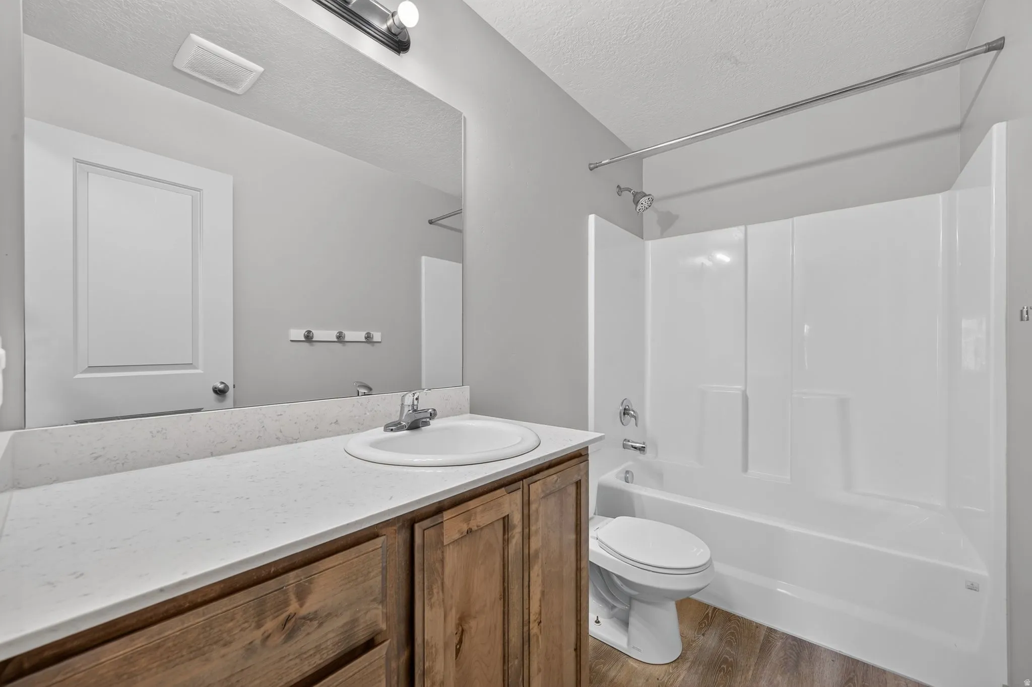 Bathroom featuring wood-finish vanity with an integrated sink, a spacious countertop, and a shower-bathtub combination