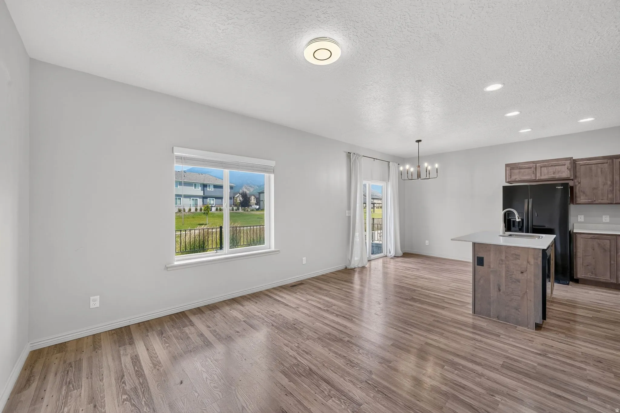 Open-concept living space featuring wood-finish flooring, a kitchen island with a light-toned countertop, dark wood-finish cabinetry, and a sliding glass door for outdoor access