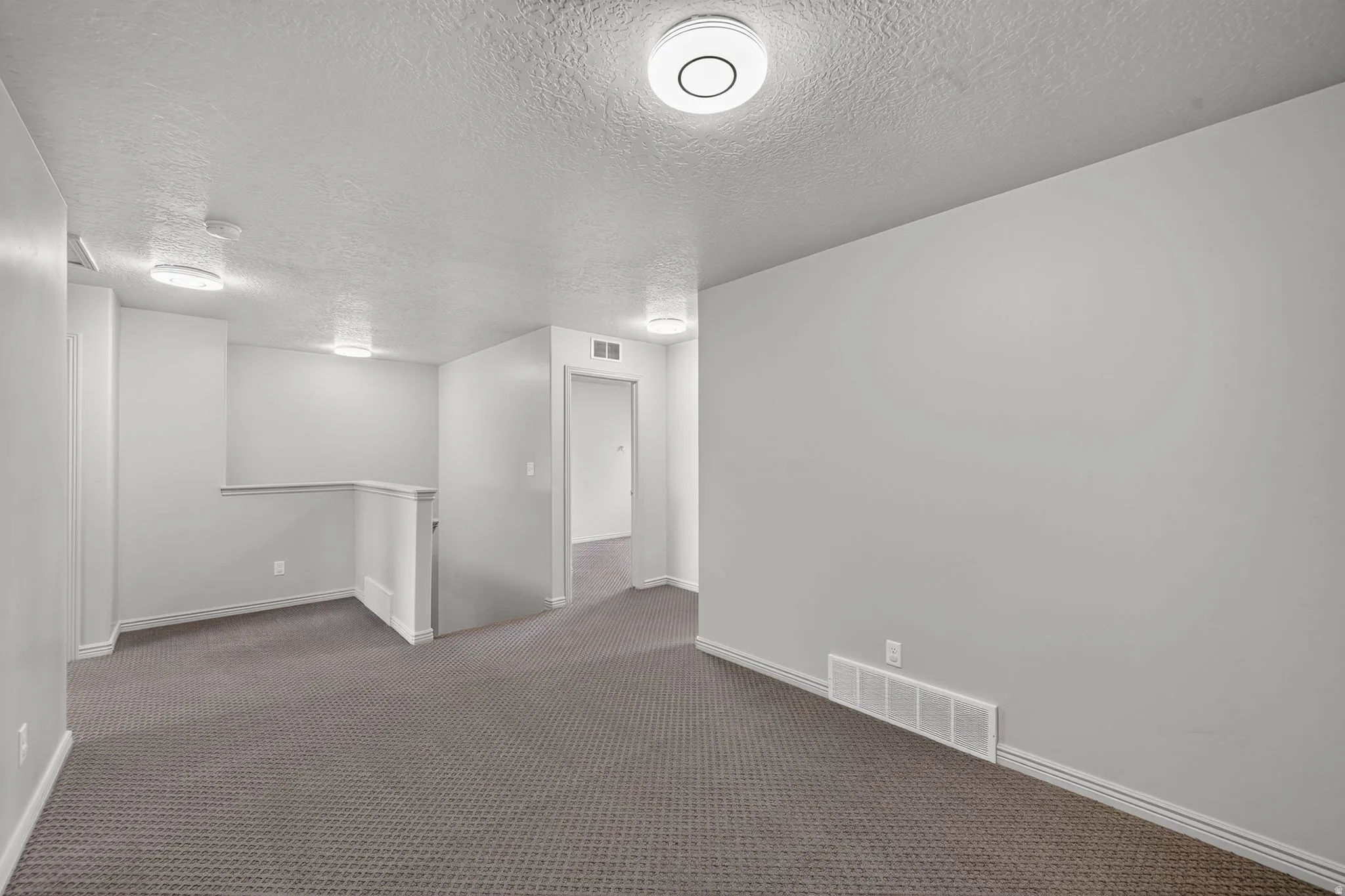 Carpeted interior area with neutral wall tones and multiple flush-mount ceiling lights