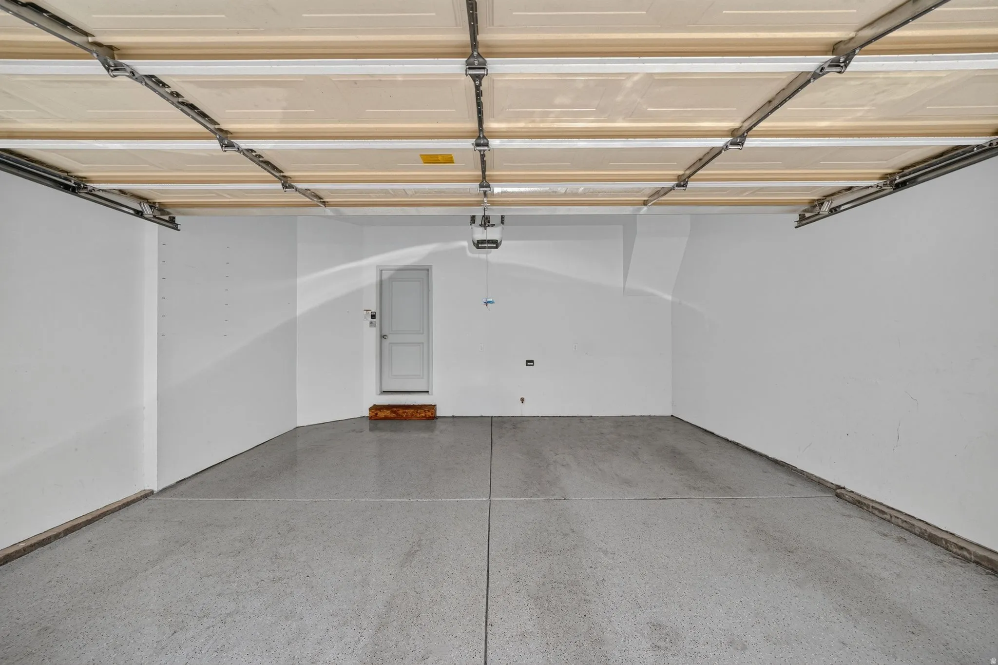 Spacious garage featuring a durable epoxy-coated floor, painted walls, and an automatic garage door opener