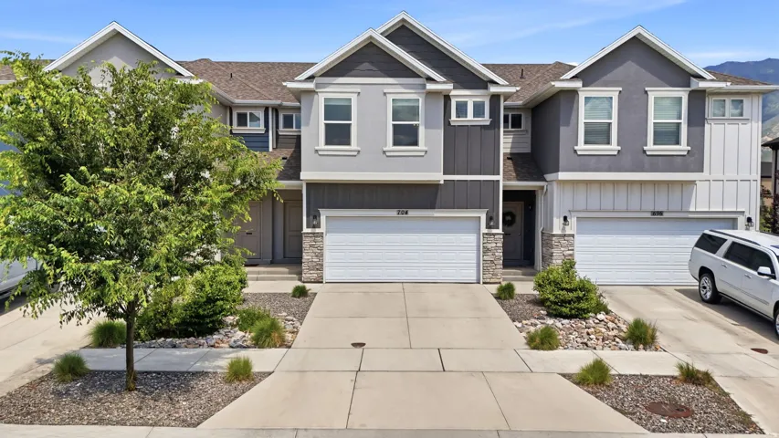 Modern townhome facade featuring a two-car garage, stone accents, and a contemporary color palette