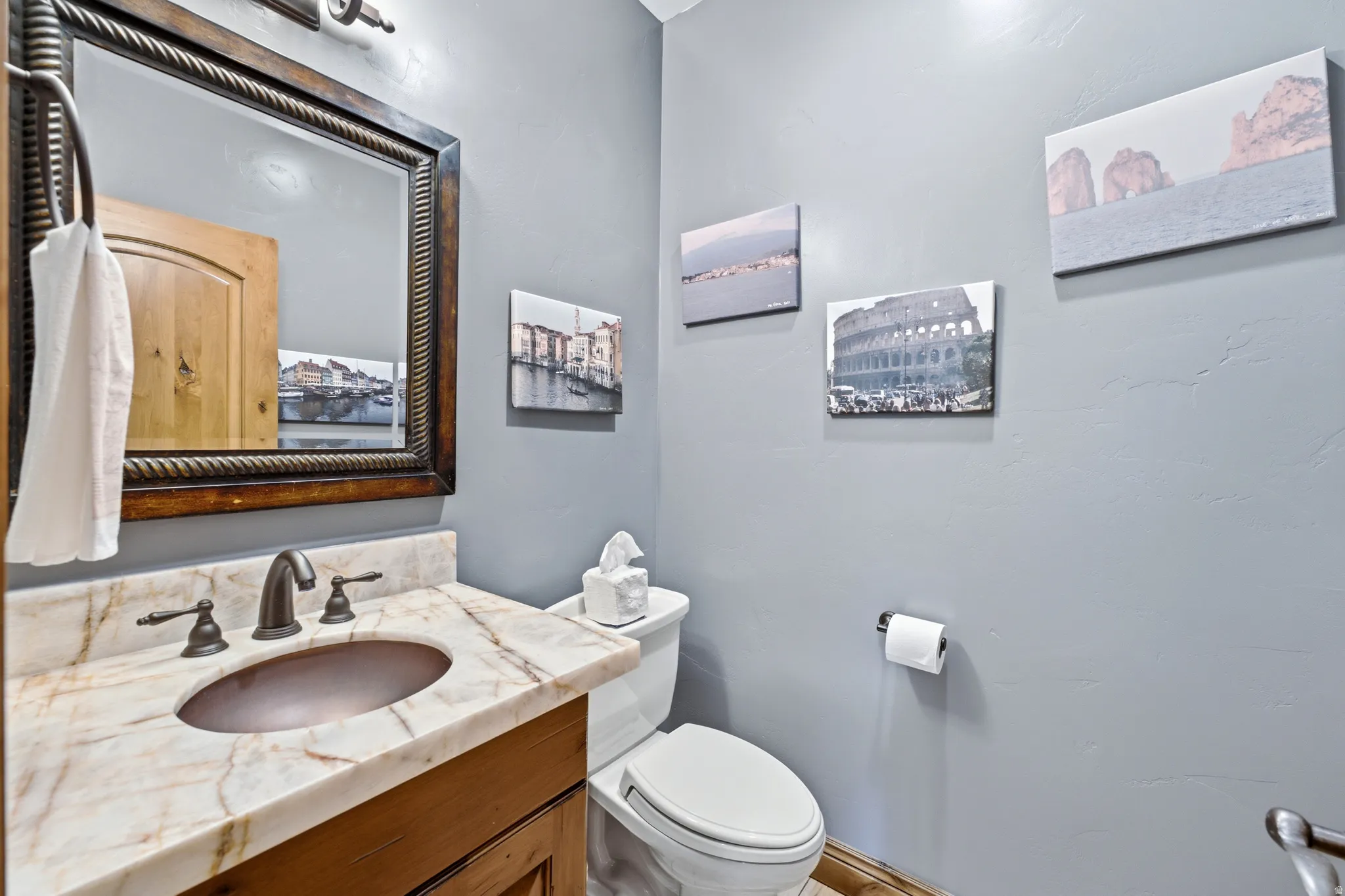 Poweder room 1/2 Bathroom featuring a stone-top vanity with an undermount sink, bronze-finish faucet, and coordinating framed mirror