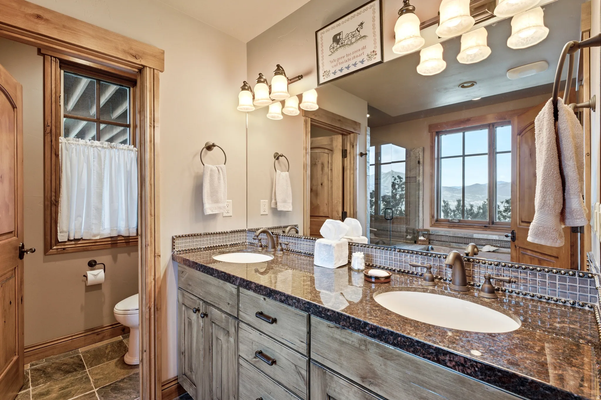Bathroom featuring a double vanity with granite countertop, integrated sinks, and bronze-finish fixtures