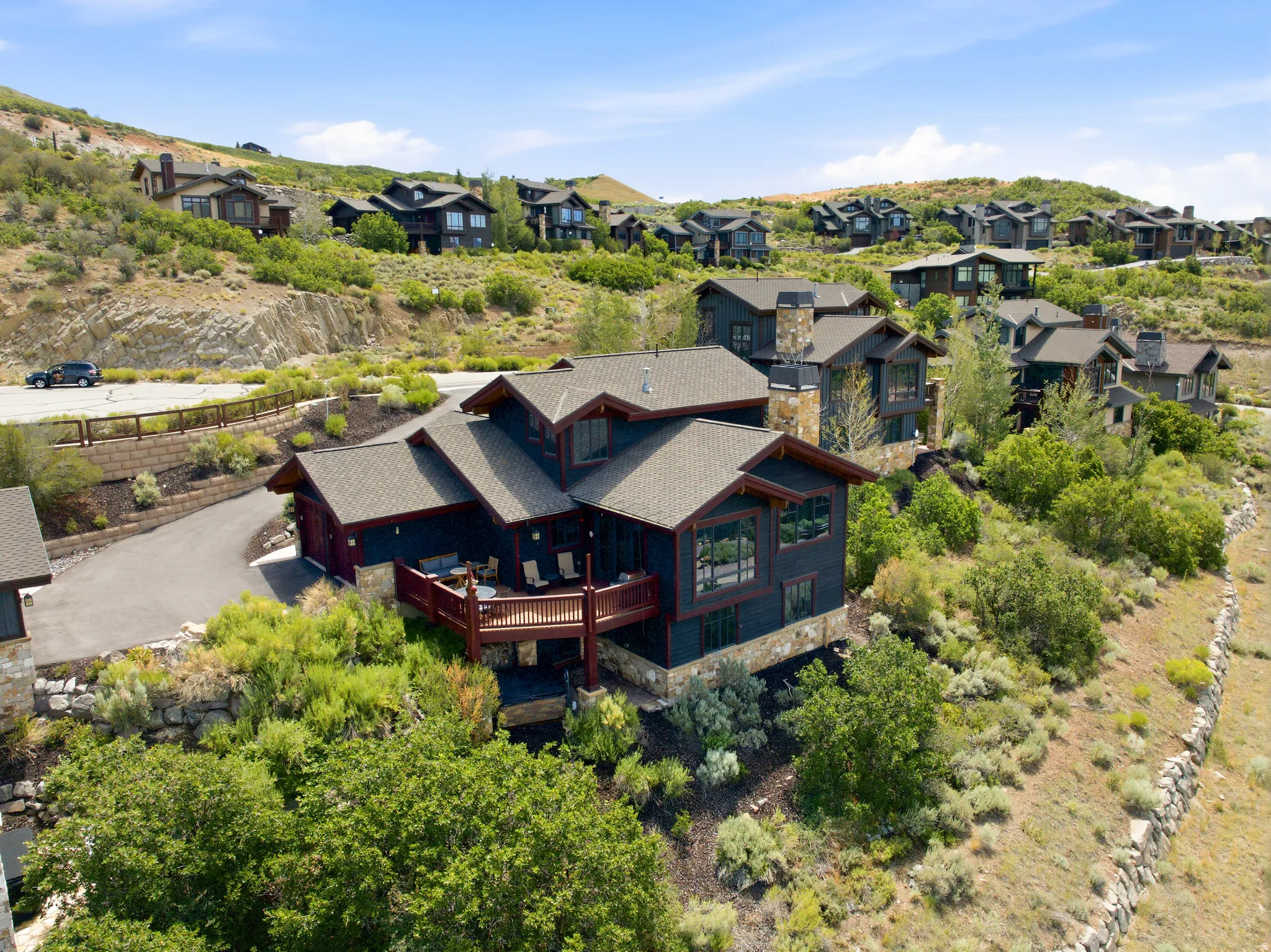 Hillside residence featuring multiple levels, dark siding, and stone accents