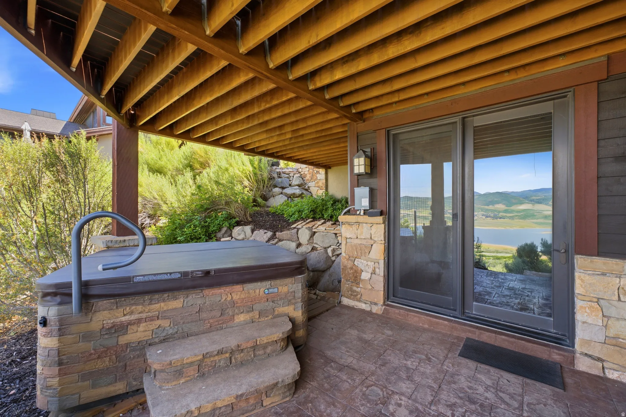 Patio featuring a built-in spa with stone surround, concrete paver flooring, and sliding glass doors