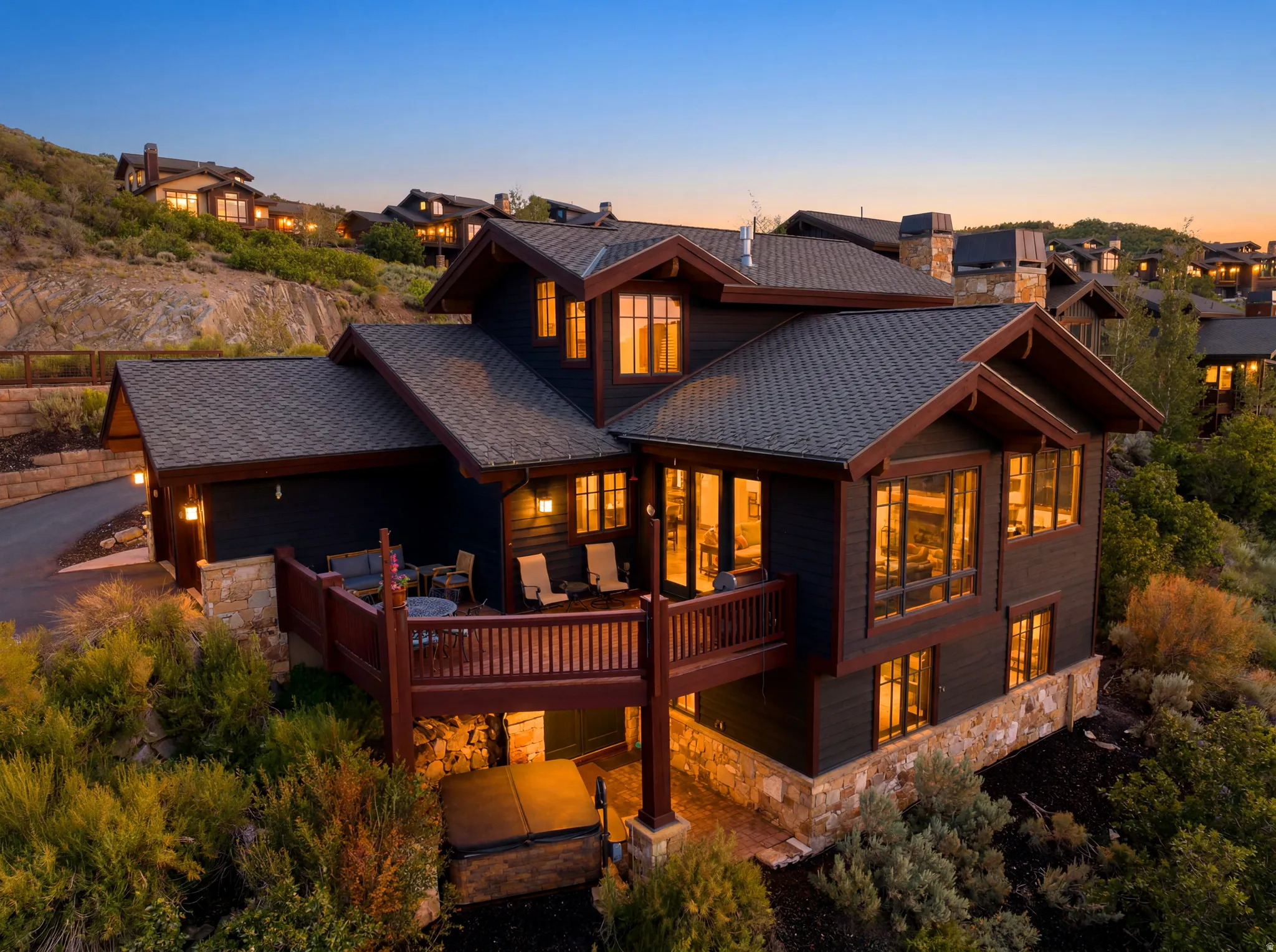 Multi-level residence featuring dark siding, stone accents, and a shingle roof